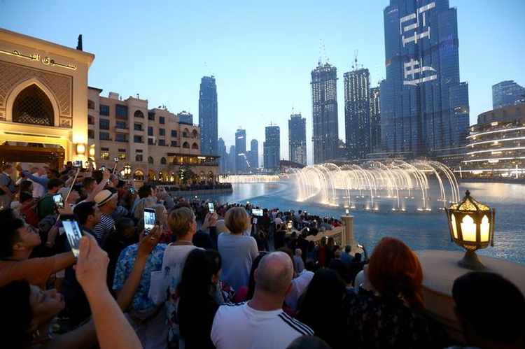 People watch a musical fountain in front of the Burj Khalifa, the tallest building in the world, in Dubai